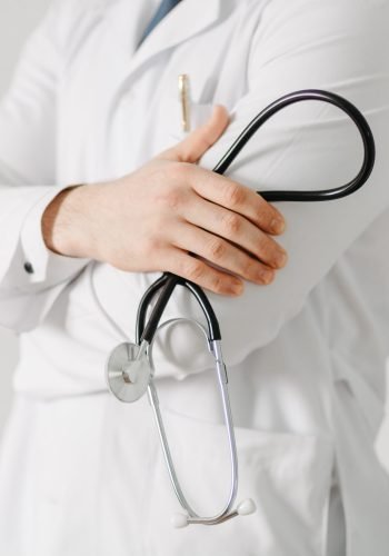 Portrait of a friendly doctor. Isolated on gray